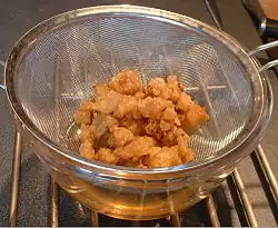 Straining the solid cracklings from the rendered fat