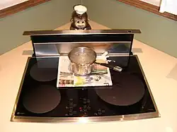 A cooktop with a saucepan of boiling water in it, and a layer of undamaged newspaper beneath