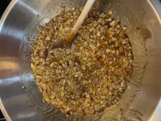 Metal bowl with pecan pie filling and a wooden spoon