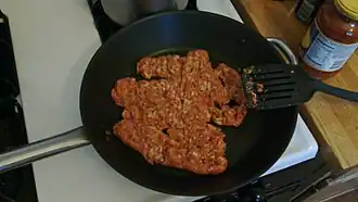 Italian-style sausage, uncooked, in a skillet.