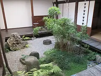 A square garden courtyard, about 2m on each side, with an engawa of broad dark boards about 30 centimetres (12 in) above the pale gravel.