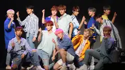 The members of Seventeen hold up finger hearts as part of the choreography for "Oh My!" at a showcase in 2018.