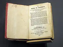 A photograph of the 1841 First European (London) edition of the Book of Mormon. It is open to its title page. The edges of the page are colored red.