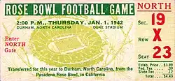 A game ticket featuring the text: Rose Bowl Football Game. 2:00 P.M., Thursday, Jan. 1, 1942. Durham, North Carolina. Duke Stadium. Enter North Gate. Transferred for this year to Durham, North Carolina, from the Pasadena Rose Bowl, in California. NORTH Sec. 19 Row X Seat 23. The ticket's price is $4.40, and behind all the text is an illustration of an aerial view of the Rose Bowl Stadium in Pasadena.