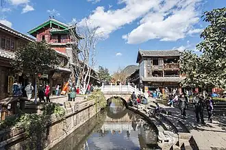 Traditional houses on both sides of a stream, crossed by a stone bridge