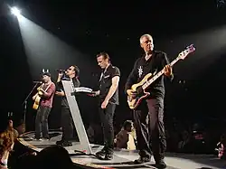 The four members of U2 standing alongside each other during a concert performance.