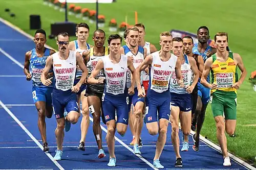 Photo with Henrik, Jakob, and Filip Ingebrigtsen running side by side ahead of a group of other runners on blue tracks