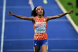 Photo of Sifan Hassan holding up her arms after winning the 5000 metres on blue tracks