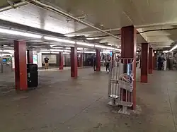 The mezzanine of the 47th–50th Streets–Rockefeller Center station. There are several passengers walking toward a turnstile in the background.