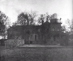 Black and white photo of a two-storey mansion with an astronomer's observatory on the roof