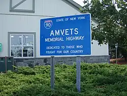 A blue sign with the I-90 sign and "AMVETS Memorial Highway"