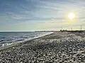 View of East Matunuck State Beach looking west from the start of the fully public portion of the beach. It shows the row of lifeguard chairs and the pavilion.