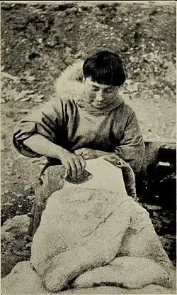 Ada Blackjack removing blubber from a sealskin
