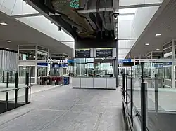 Inside a building with fare gates and lifts that lead down to platform level