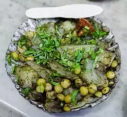 Alu kabli, a Bengali alu chat made with sliced boiled potatoes, chickpeas, tomatoes, cucumbers, tamarind sauce, Bengali spices, and chopped chillies, and garnished with coriander leaves
