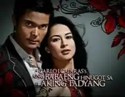 An image of Dingdong Dantes and Marian Rivera, over a gray background. The series title is displayed on the lower part of the image. The texts "Carlo J. Caparas's" are written above the series title.