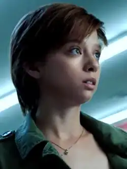 Lore, a white woman with cropped red hair wearing a green jacket