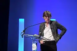 woman in business suit speaking at a podium