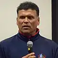 Headshot of Anthony Munoz holding a microphone