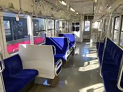 The interior of a train carriage with blue fabric seats and large windows