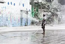 A man holding a hose and spraying volcanic ash with water