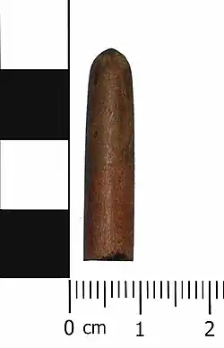 A wooden bullet shaped object. It is smooth all over and brown in colour. probably used for practice firing. Rather than simply firing blank cartridges, some automatic weapons, particularly machine guns required a projectile in order to produce the n