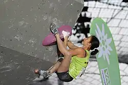 A climber using the heel-hooking technique on an indoor climbing wall