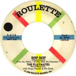 The single's label features the song title, artist, publisher, and other details in black typefaces; the background is white with eight evenly-spaced multicolored spokes radiating from the center hole.
