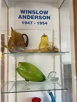 display of products by Winslow Anderson including gold colored wares and a green fish vase