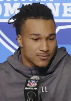 Brian Branch standing at a podium at the NFL draft.