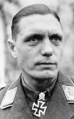 A man wearing a military uniform with an Iron Cross displayed at the front of his uniform collar.