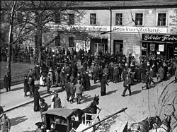 A large number of people crowd outside a building.