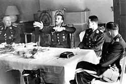 Black-and-white photograph of four men wearing uniforms sitting at a table.