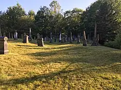 Grave stones in a grassy field.