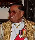 Chai Chidchob wears the Second-Class Ministerial Gown (ครุยเสนามาตย์ชั้นโท; Khrui Senamat Chan Tho). A recipient of the first or second class of the Order of Chula Chom Klao is entitled to wear this gown.