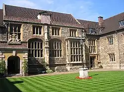 A courtyard of a set of stone buildings with large windows.