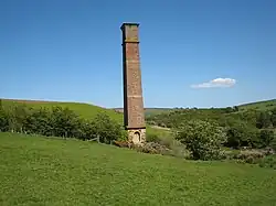 A tall brick chimney surrounded by green fields