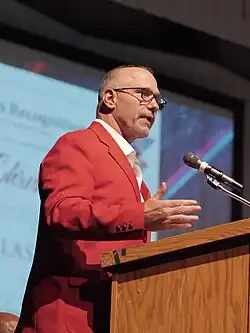 Chris Spielman in a red suit standing a podium.