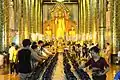 Inside the wihan of Wat Chedi Luang, money offerings are dropped into alms bowls during the festival