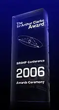 A glass 2006 Clarke Award, stating in white text "The Sir Arthur Clarke Award. BROHP Conference, 2006 Awards Ceremony".