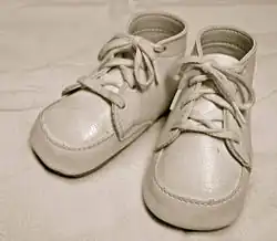 Small pair of white laced baby shoes on display