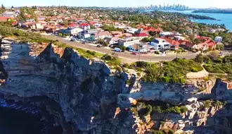 Sydney Harbour in distance as seen aloft from Tasman Sea, overlooking the clifftop suburb of Vaucluse