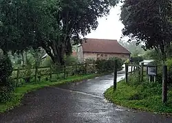 Road with a small stone barn in the top of the image.
