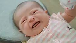 an Asian newborn crying and looking upset with its mouth open