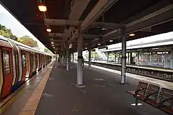 Island platforms covered in a canopy and a modern London Underground train with doors open