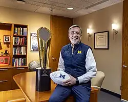 Grasso in his Dearborn office with the 2024 NCAA National Football Championship trophy on loan from Ann Arbor