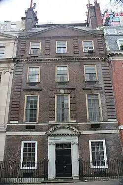A brownish brick townhouse with stone trim