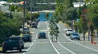 Boulevard with cars parked on each side, with river in background