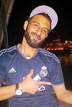 Egyptian man wearing a sports shirt and a hat as part of a globalized streetwear trend, 2019.