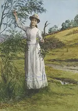 Eliza Ashton in a white dress standing under a wattle tree in a field of grass